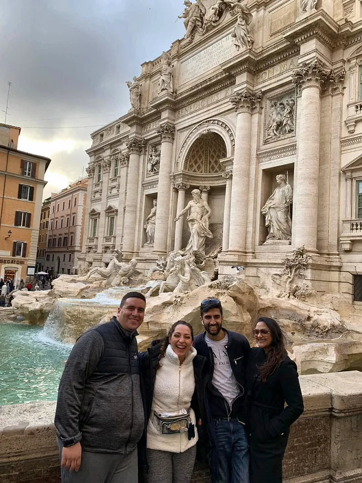 Four friends smiling at the Trevi Fountain