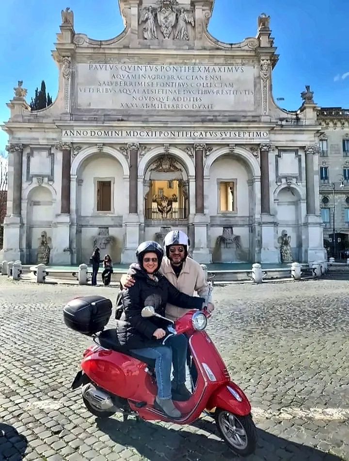 A couple on a red Vespa in front of the Acqua Paola fountain on the Janiculum