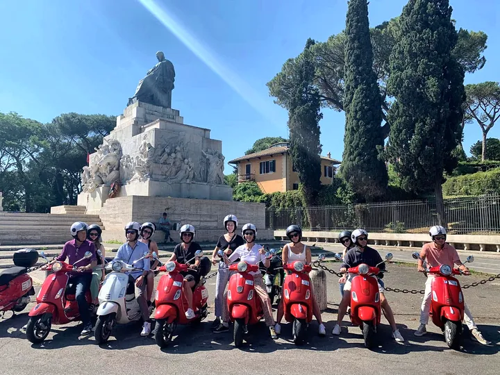 A group lined up on red Vespas before the ride